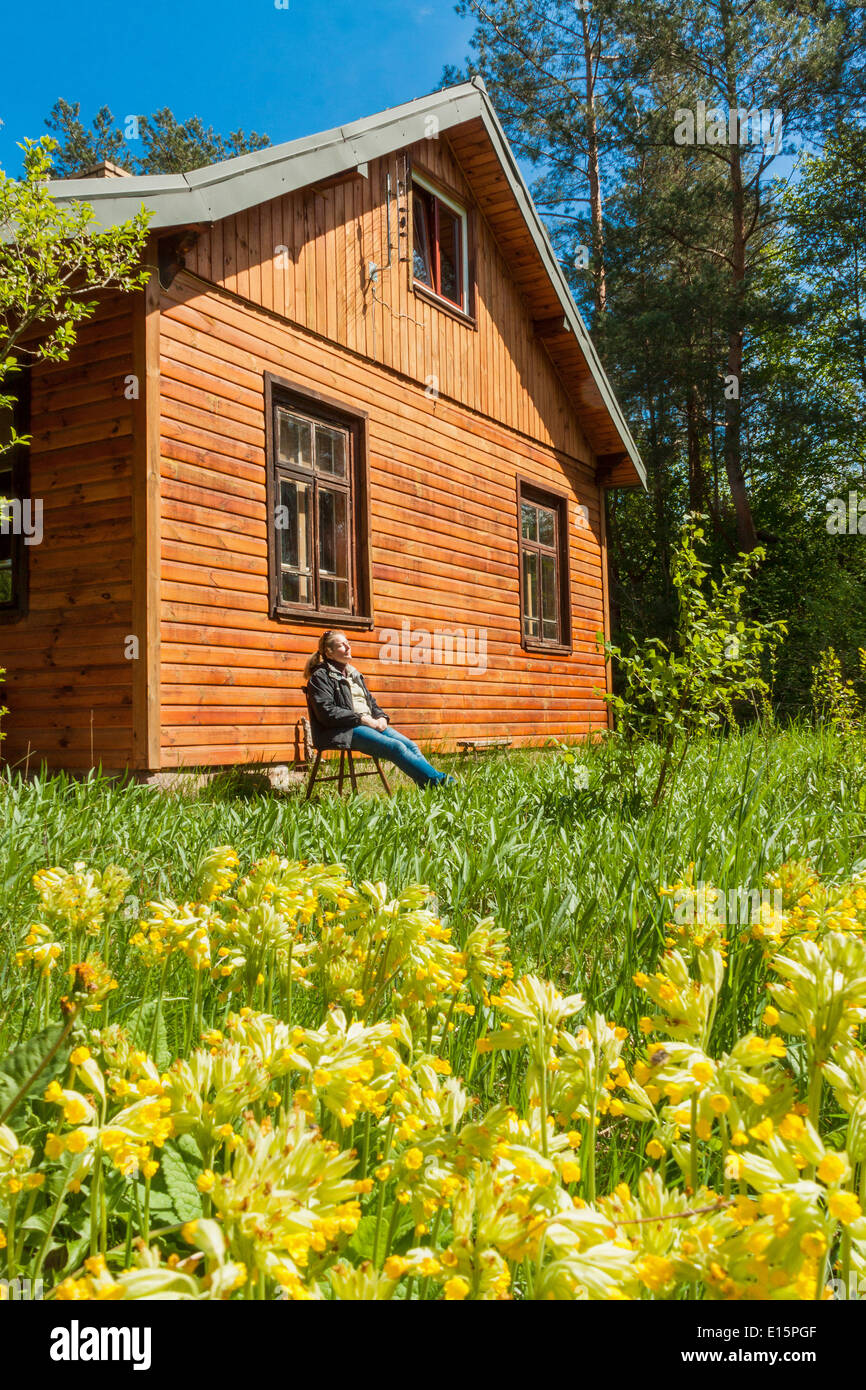 Donna crogiolarsi nella primavera sole fuori forester house Foto Stock