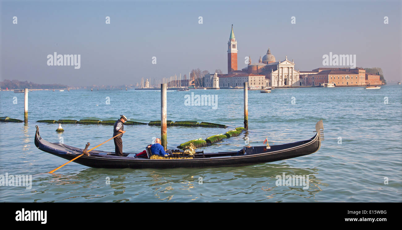 Venezia, Italia - 14 Marzo 2014: gondoliere sulla laguna e la chiesa di San Giorgio Maggiore nella luce della sera Foto Stock
