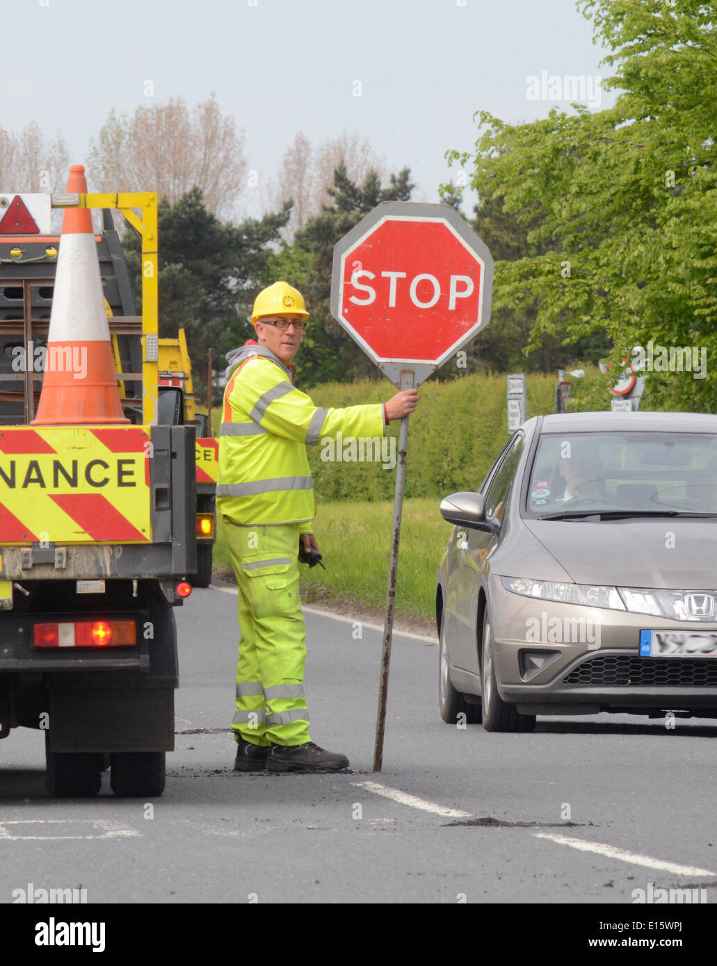 Operaio edile utilizzando lollipop stop - andare a firmare per il controllo del traffico in corrispondenza di cantieri stradali regno unito Foto Stock