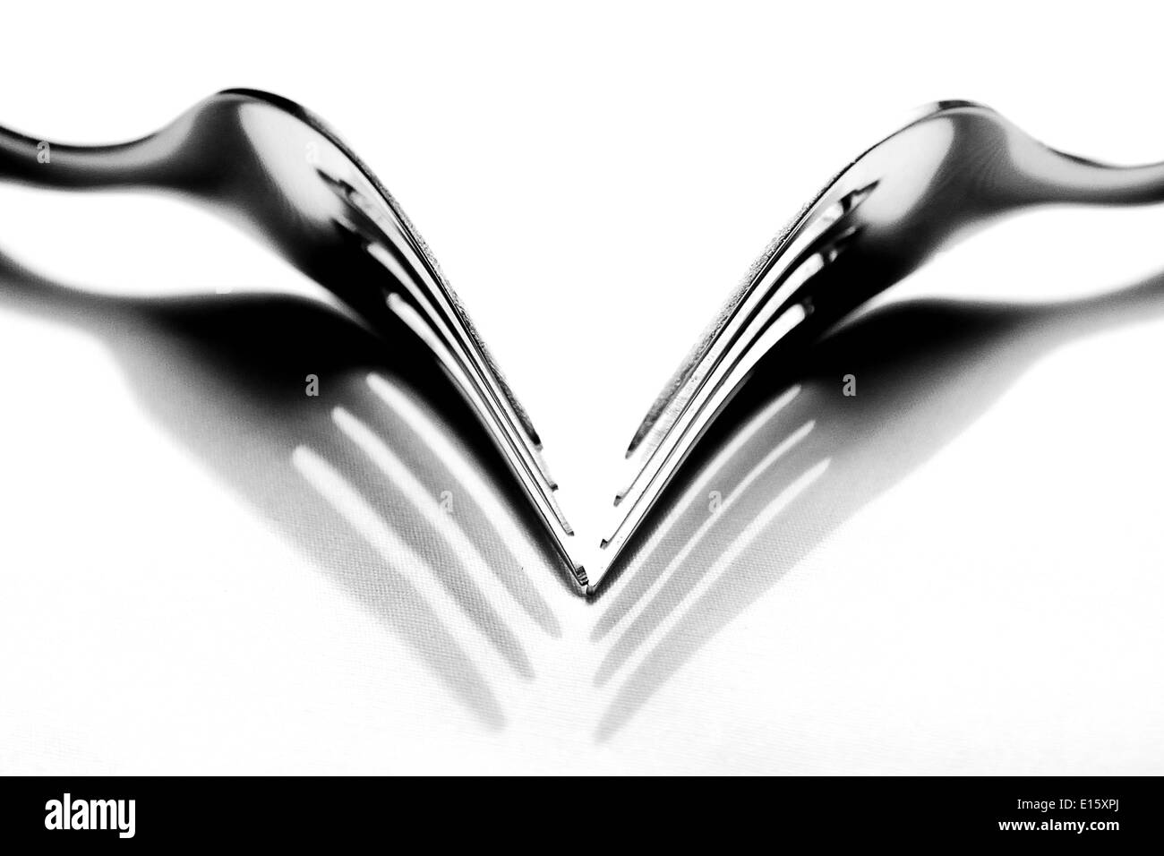 Una tabella top shot di due forcelle da pranzo gettando le proprie ombre presi in bianco e nero e il rendering in una elevata modalità chiave. Foto Stock