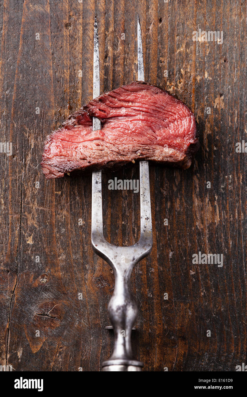 Pezzo di carne di manzo sulla carne forcella sullo sfondo di legno Foto Stock