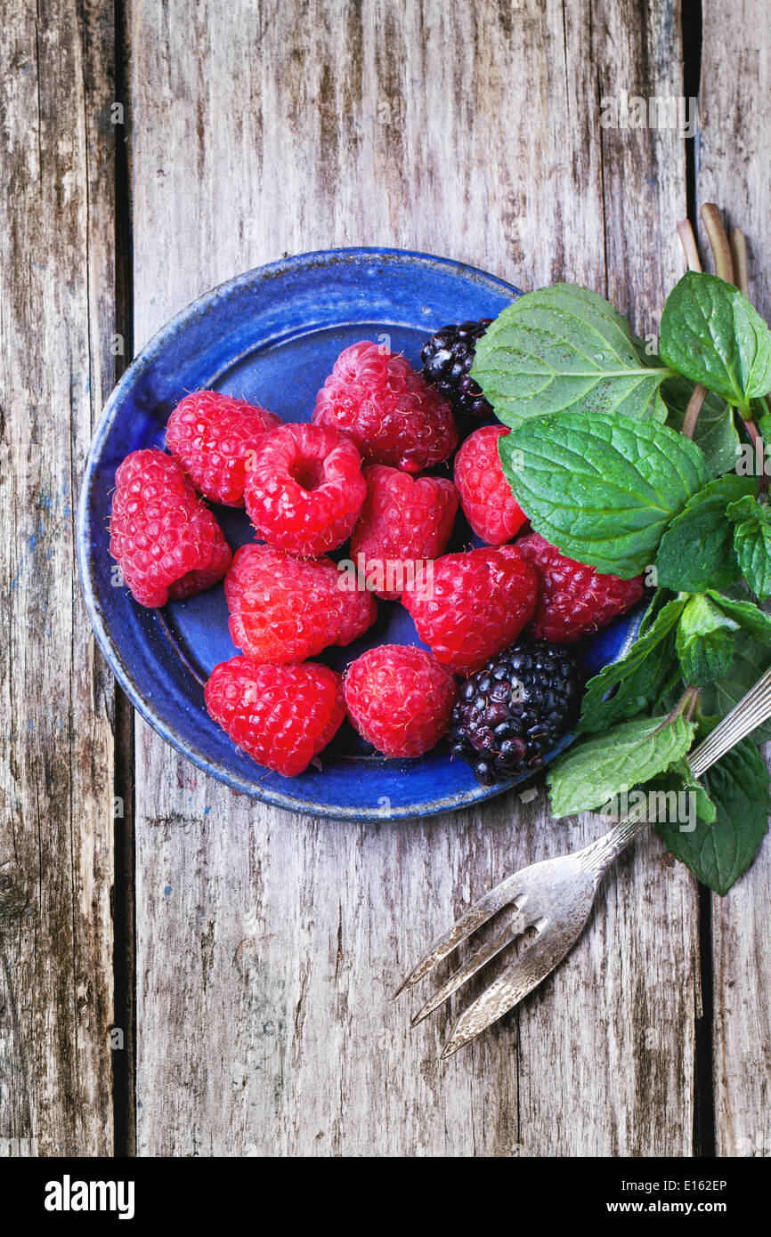 Piastra di lamponi e more servita con menta fresca e dessert forcella su un vecchio tavolo di legno. Vista superiore Foto Stock