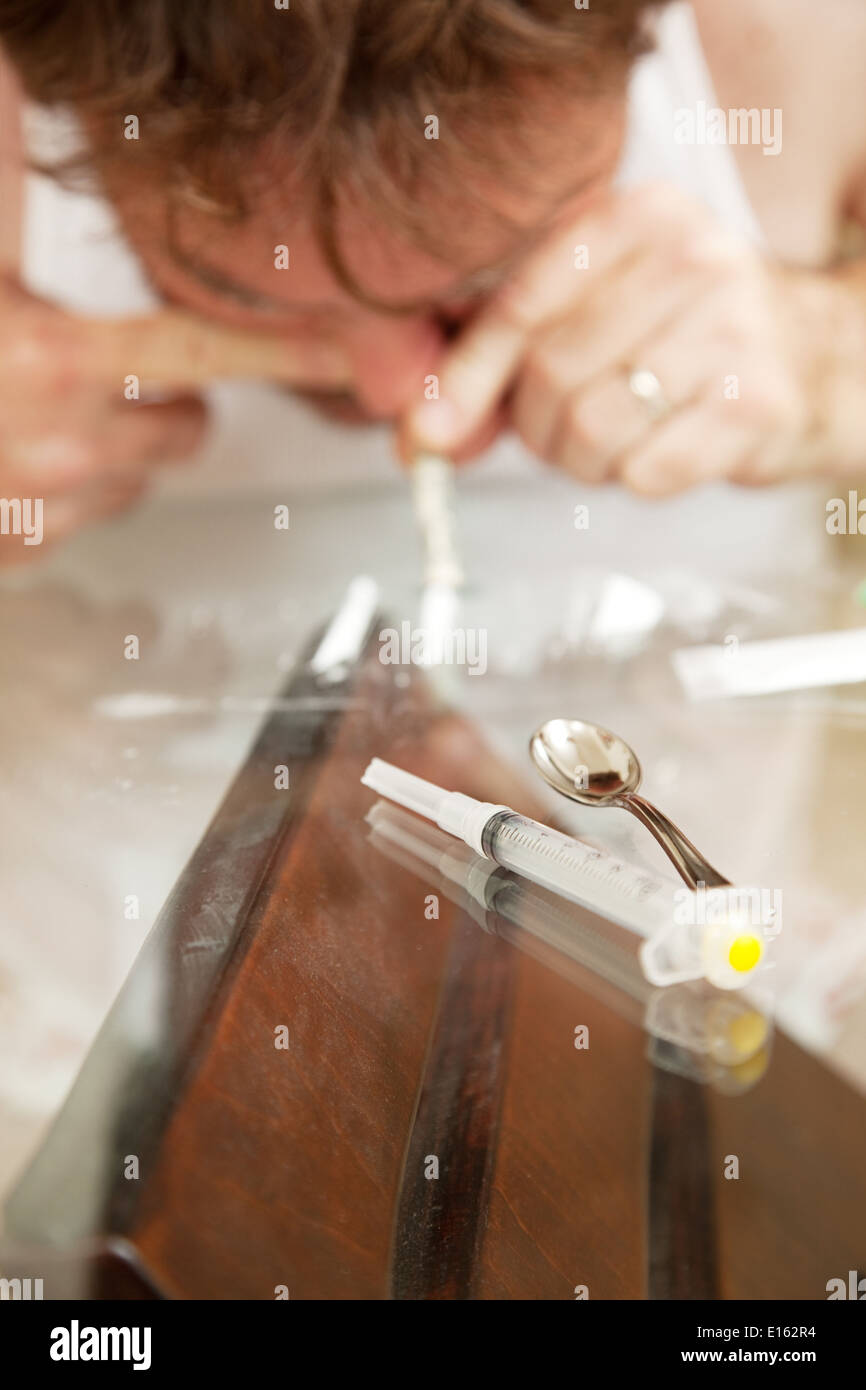 L'uomo abusa di cocaina o altro farmaco in polvere. Profondità di campo con il focus sulla siringa in primo piano. Foto Stock