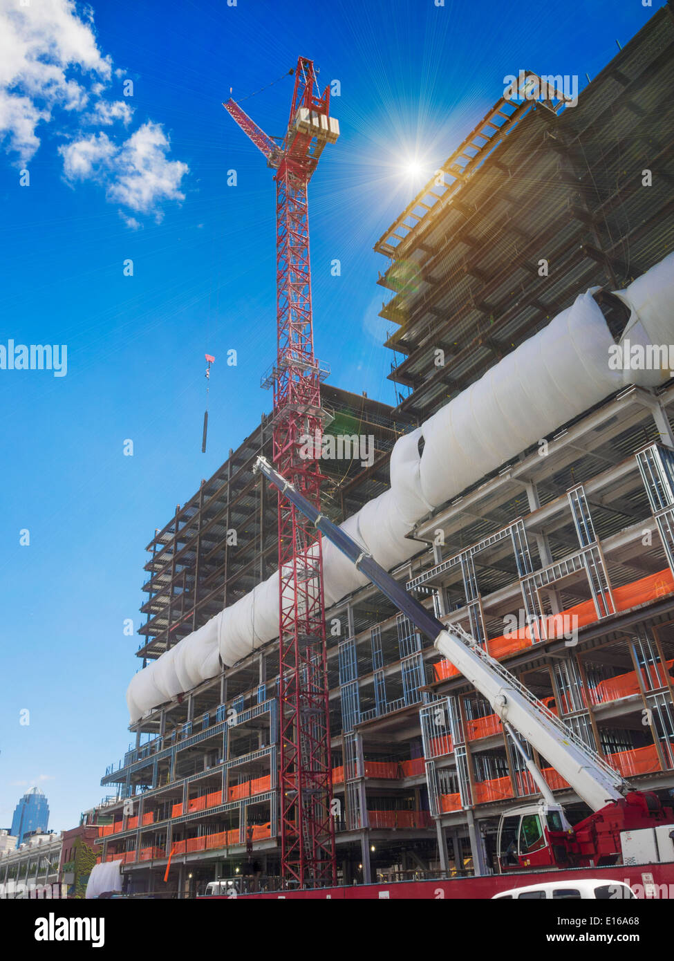 Edificio di nuova costruzione sito con gru giganti allineando travi in acciaio Foto Stock