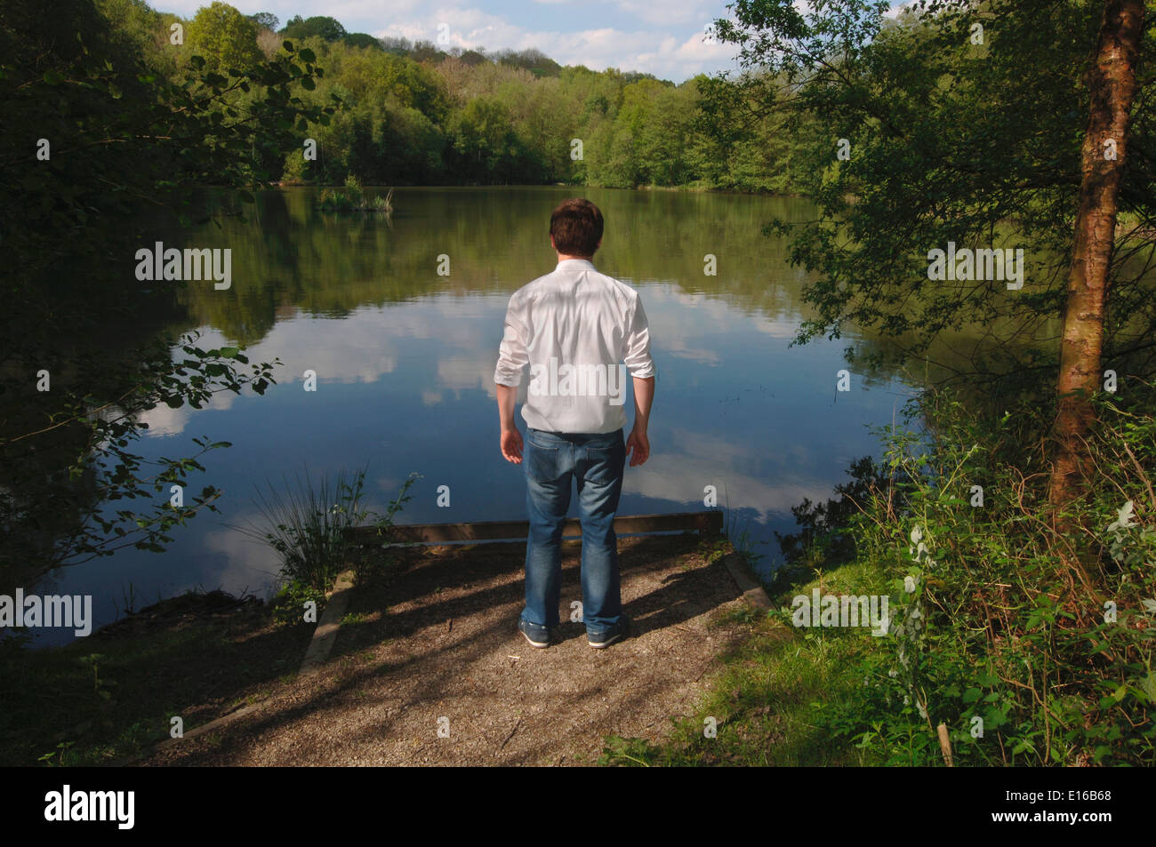 Un uomo adolescente,in piedi sul bordo di un lago di acqua dolce. Foto Stock