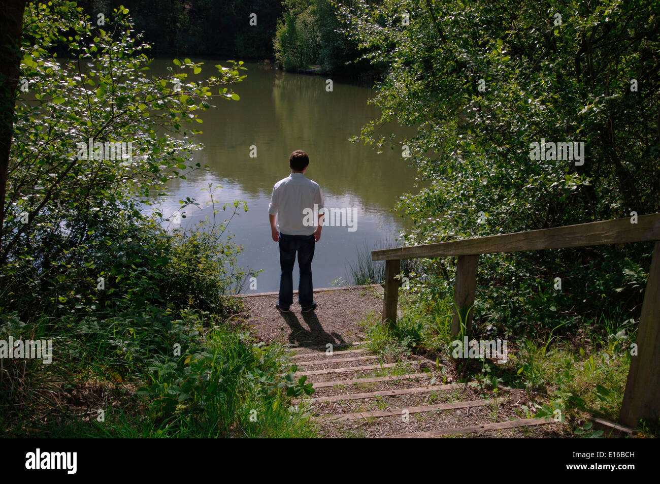 Un uomo adolescente,in piedi sul bordo di un lago di acqua dolce. Foto Stock