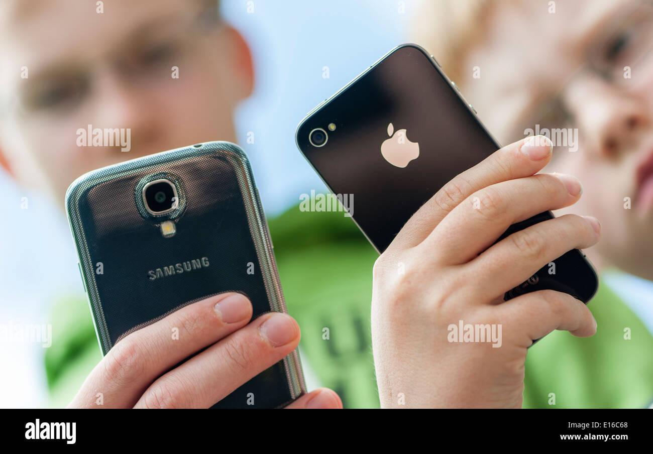 Due ragazzi sono in posa con il loro Samsung Galaxy S4 (sinistra) e l'iPhone 4 smartphone. Foto Stock