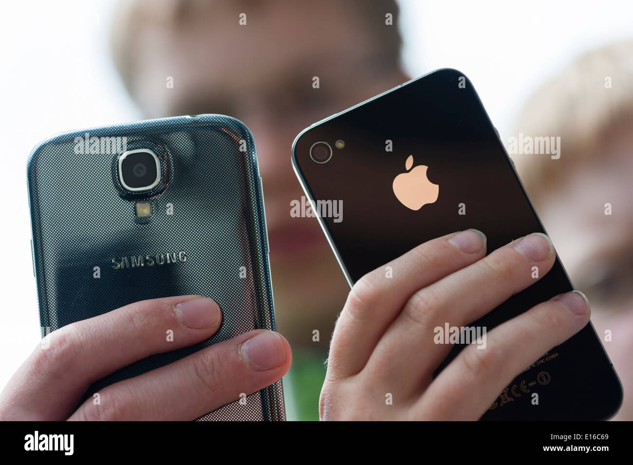 Due ragazzi sono in posa con il loro Samsung Galaxy S4 (sinistra) e l'iPhone 4 smartphone. Foto Stock
