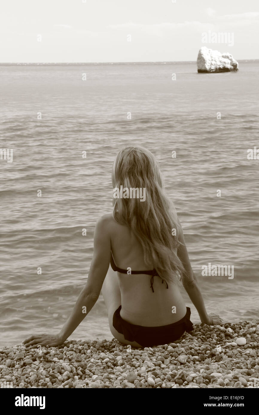Donna seduta sulla spiaggia e guardando il mare Foto Stock