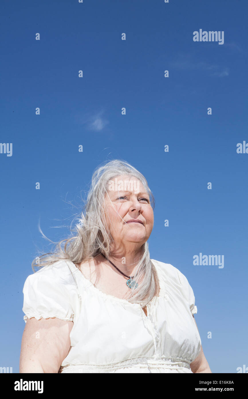 Ritratto di donna di mezza età in piedi contro il cielo blu Foto Stock