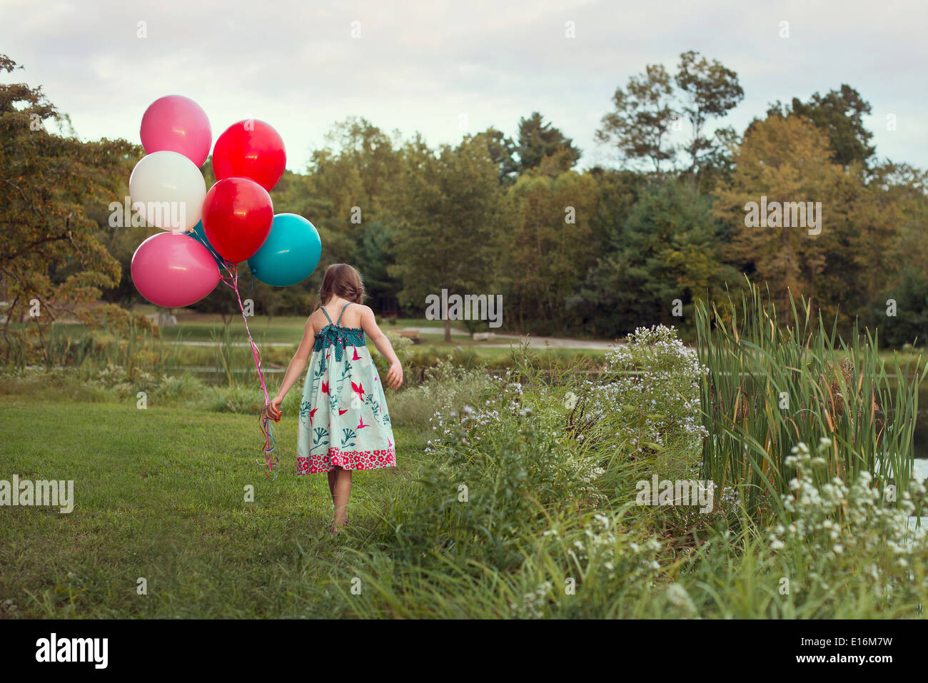 La ragazza (8-9) a piedi con palloncini Foto Stock