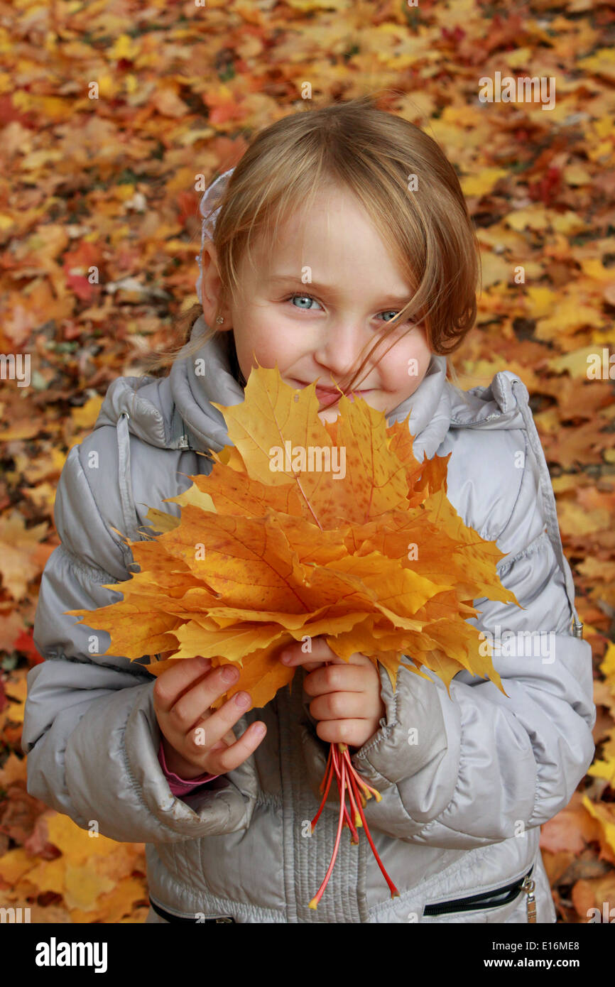 Simpatico bambina gioca con le foglie nel parco Foto Stock