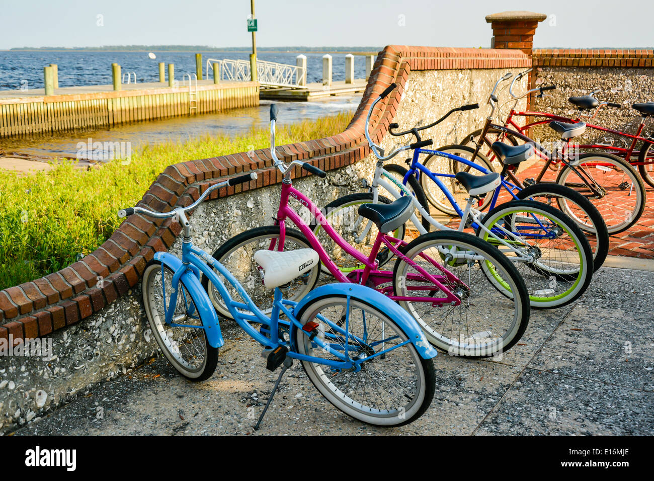 Colorata parcheggiato beach cruiser biciclette in appoggio contro una parete tabby sul lungomare porto di St. Mary's, GA, Stati Uniti d'America Foto Stock