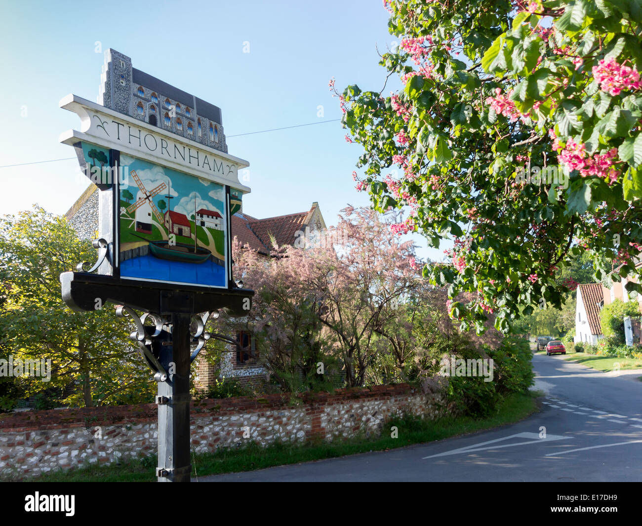 Un dipinto di firmare per il villaggio di Thornham NORFOLK REGNO UNITO, mostrando un il porto locale e il mulino a vento in primavera con tree blossom Foto Stock
