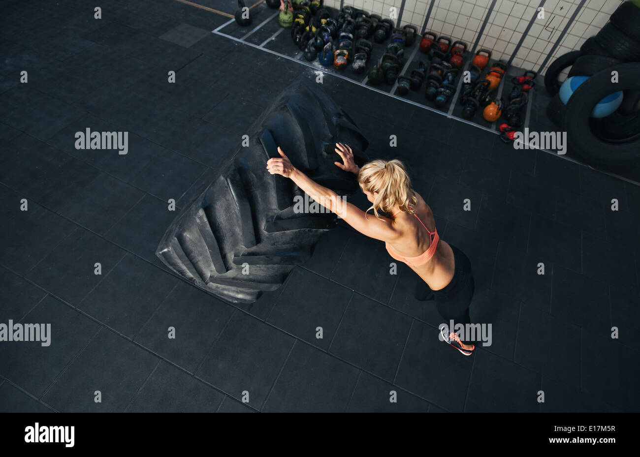 Donna Crossfit esercizi in palestra. Femmina muscolare flipping enorme pneumatico Foto Stock
