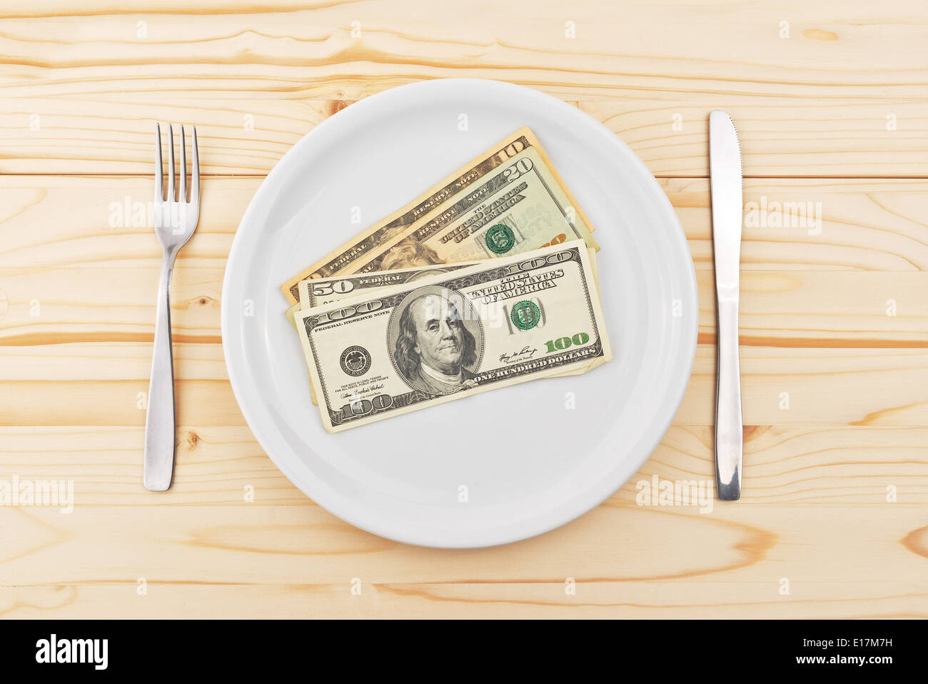Dollari USA servito sulla piastra come la cena con coltello e forchetta sui lati. Mangiare il denaro è metafora concettuale per l'avidità. Foto Stock