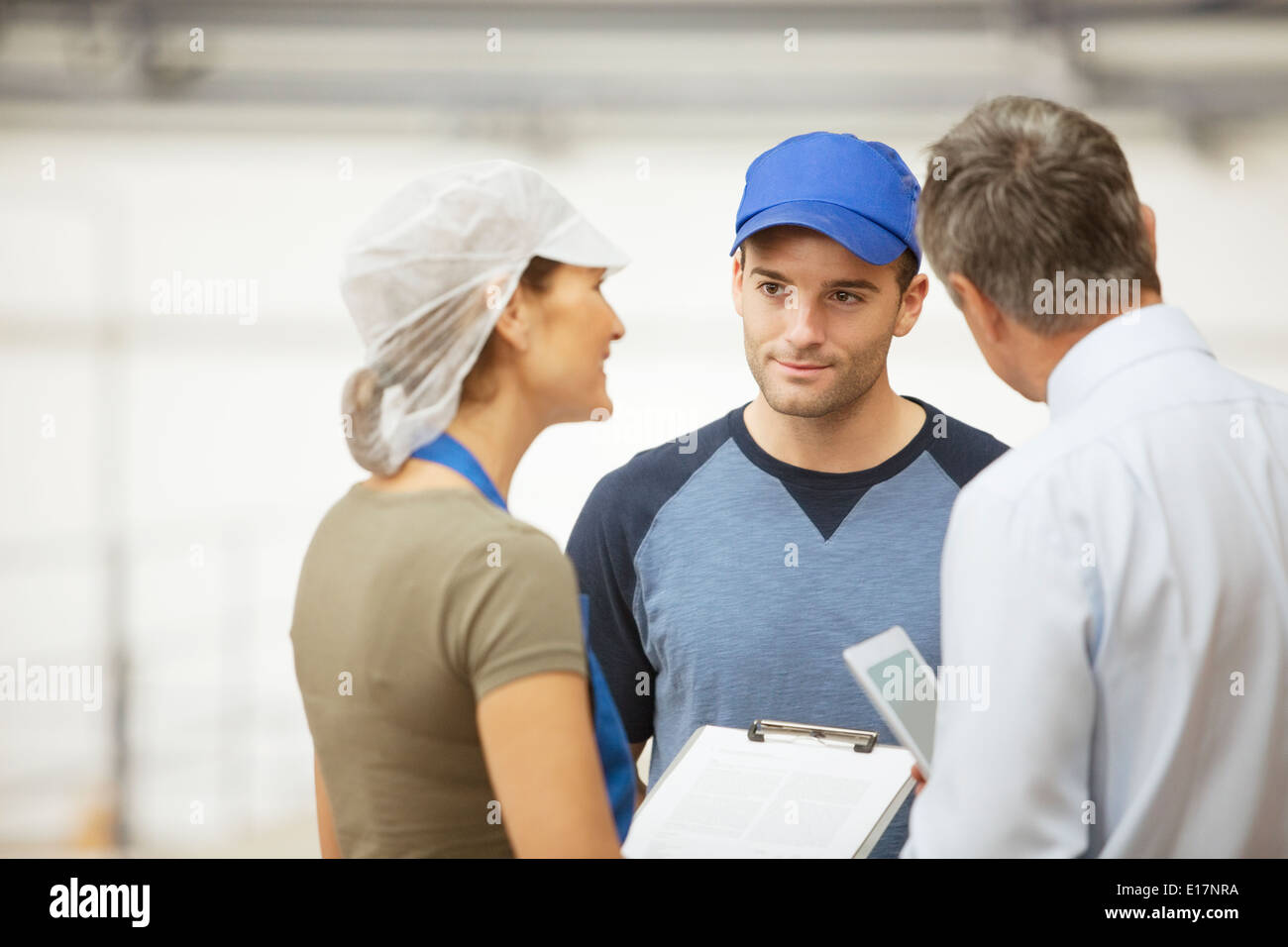 Supervisore e i lavoratori parlano in stabilimento di trasformazione alimentare Foto Stock