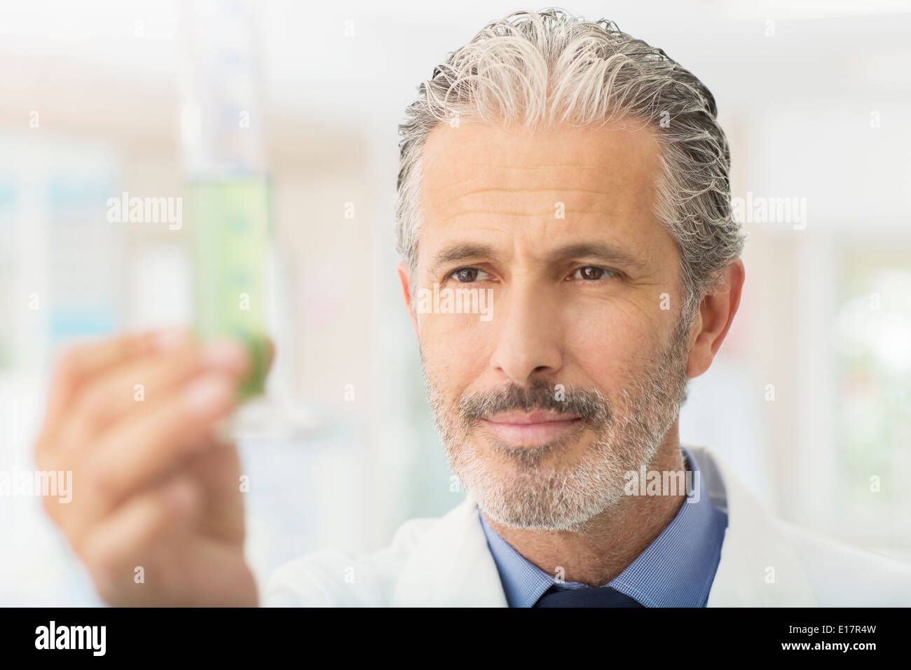 Scienziato esaminando liquido verde nel tubo Foto Stock