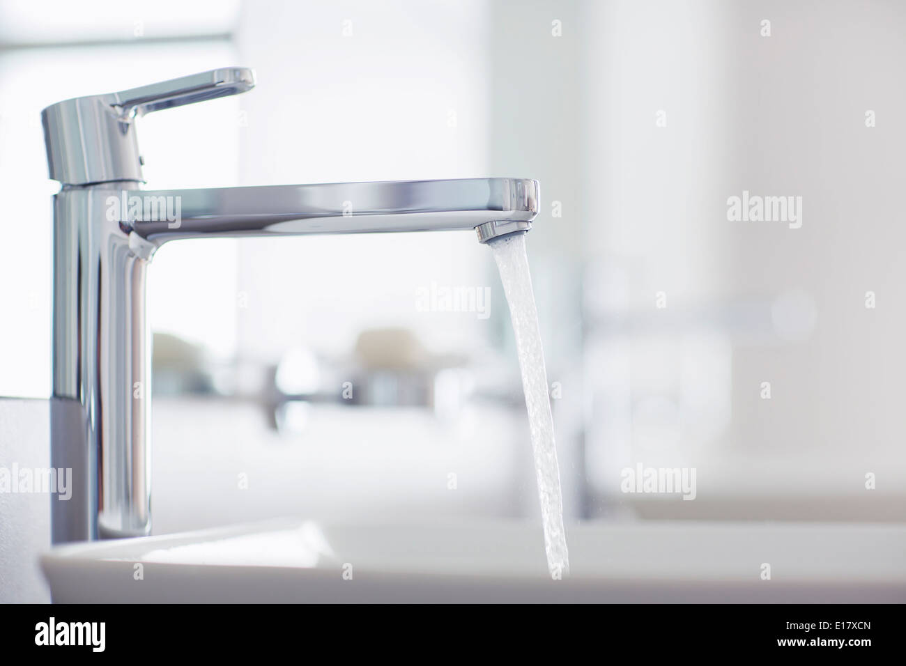 Versare acqua dal rubinetto moderno nella stanza da bagno Foto Stock