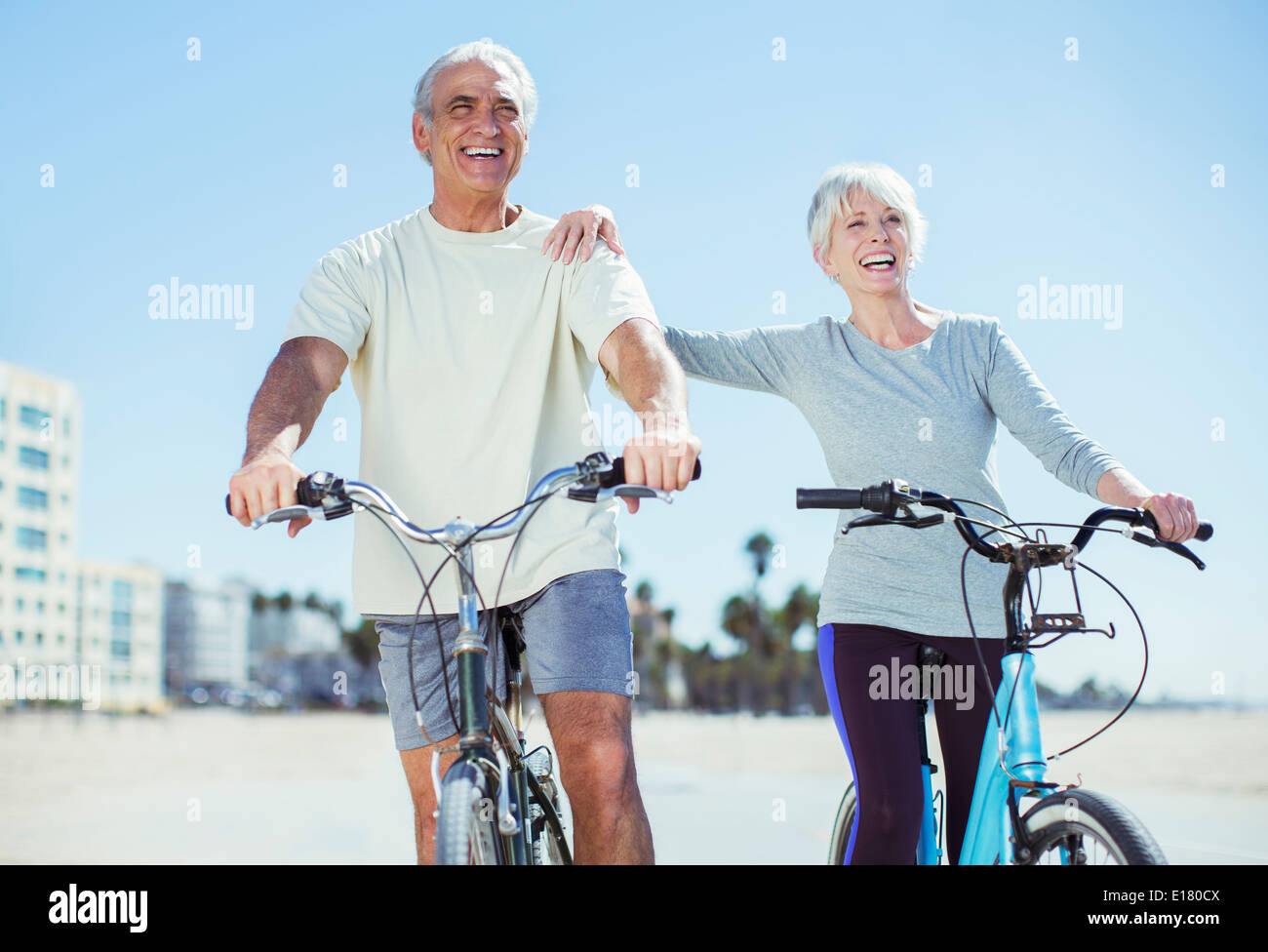 Coppia senior con le biciclette sulla spiaggia Foto Stock