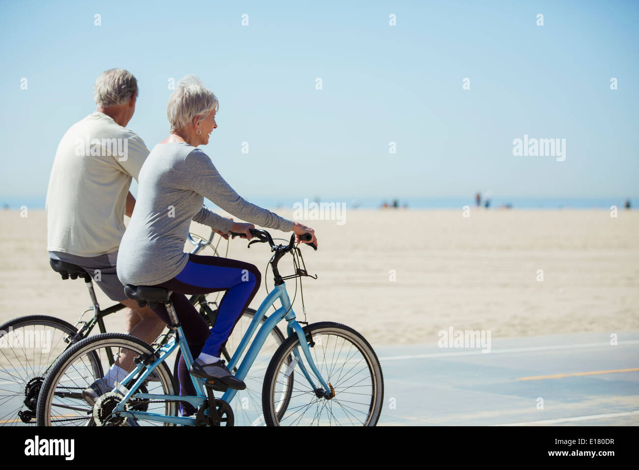 Coppia senior di andare in bicicletta sulla spiaggia Foto Stock