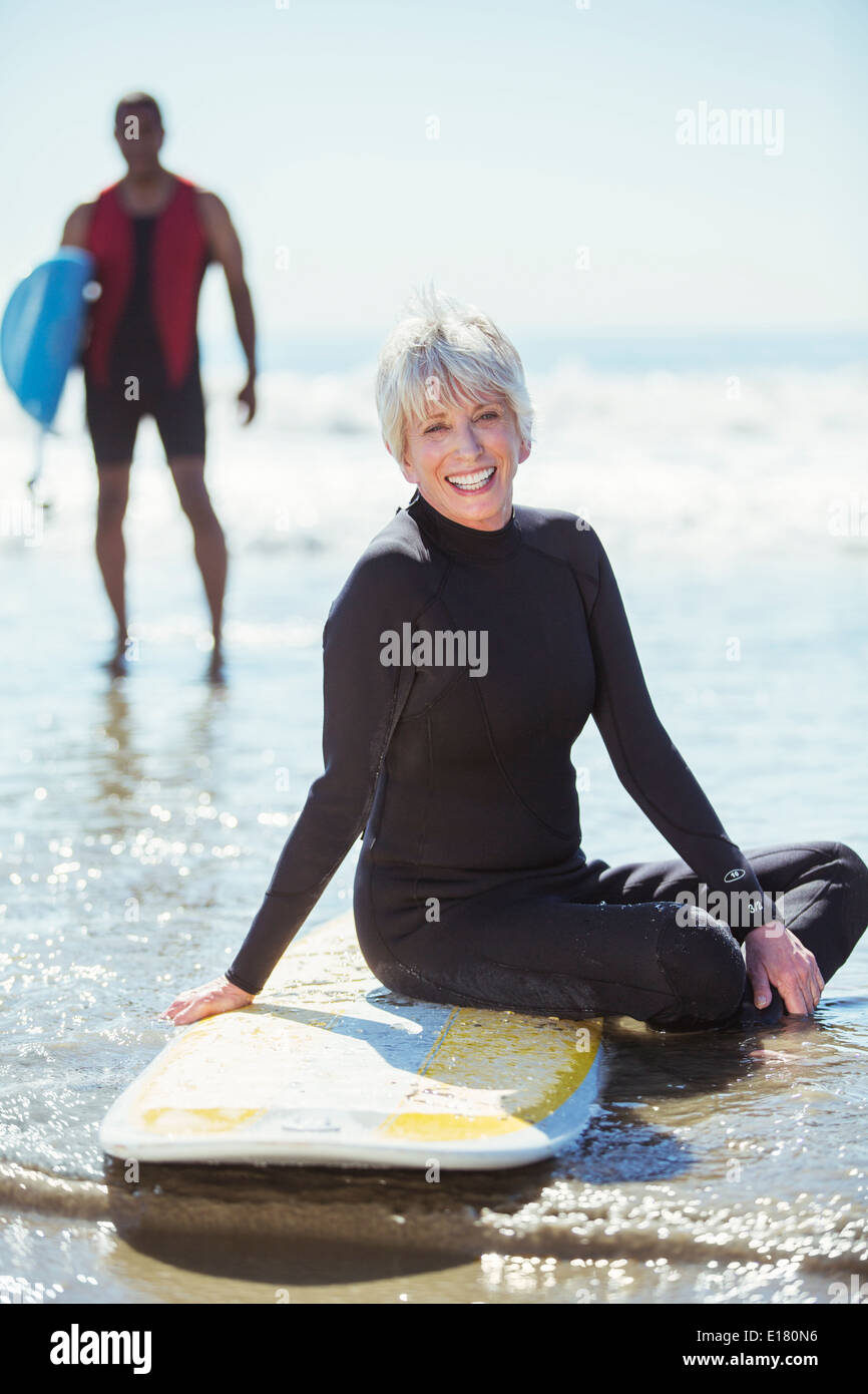 Ritratto di donna senior sulla tavola da surf in spiaggia Foto Stock