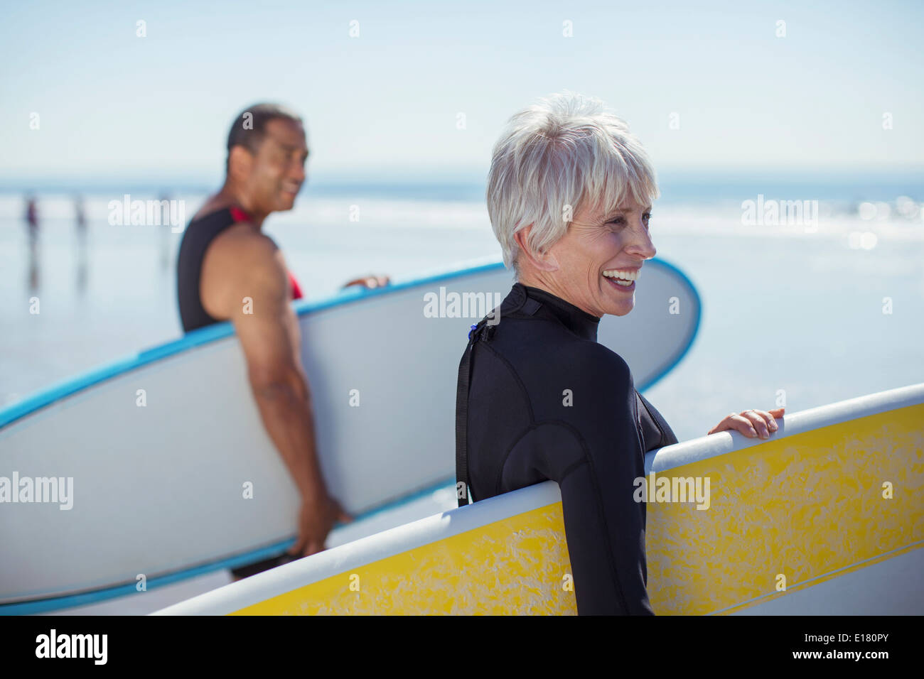 Coppia senior che trasportano le tavole da surf in spiaggia Foto Stock