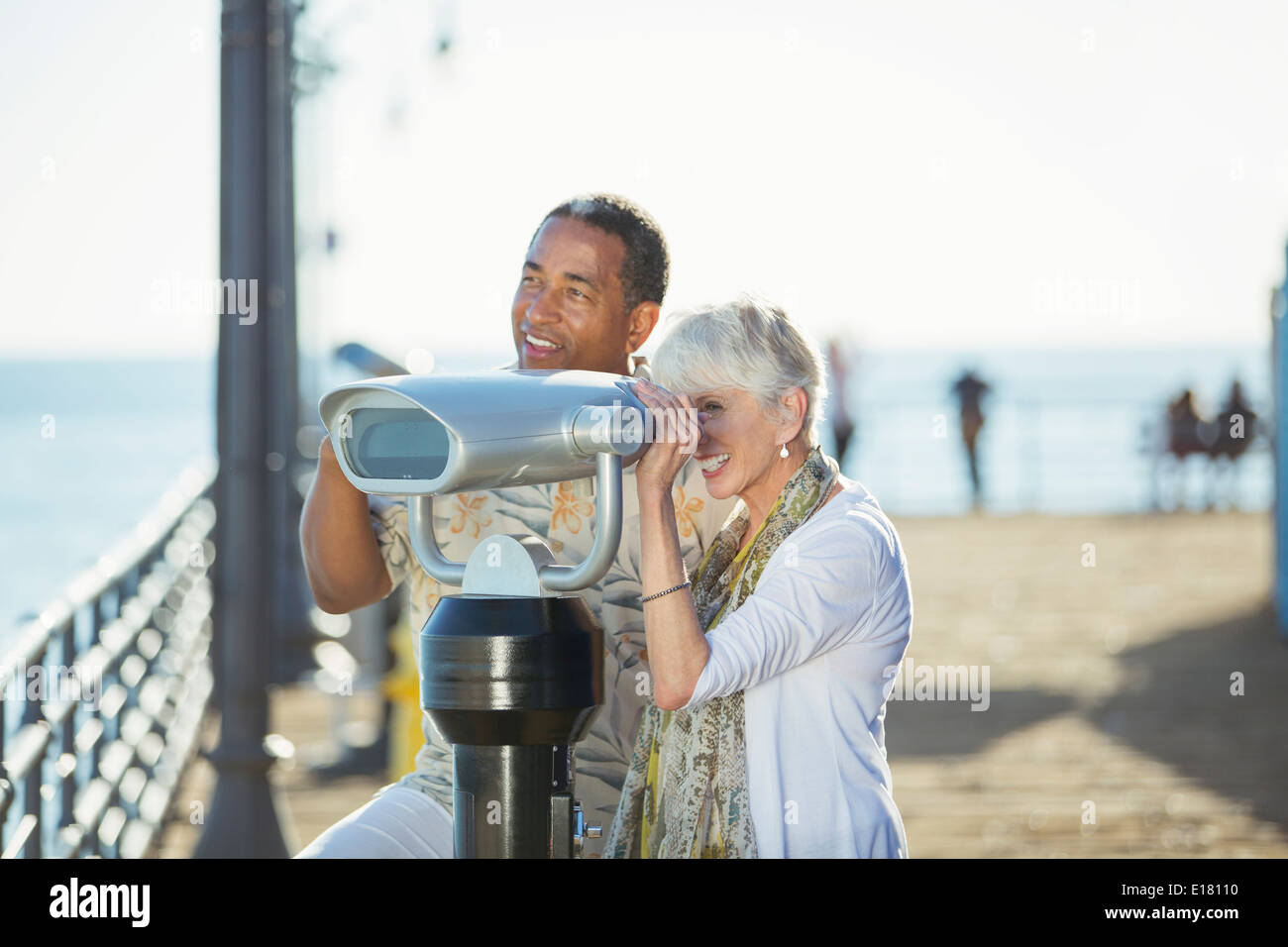Coppia senior con gettoniera binocolo sul molo Foto Stock