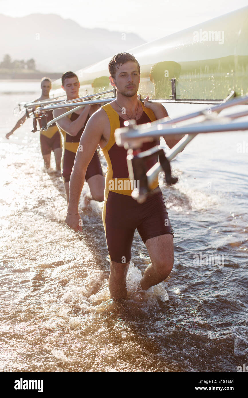 Il team di canottaggio che trasportano scull nel lago Foto Stock