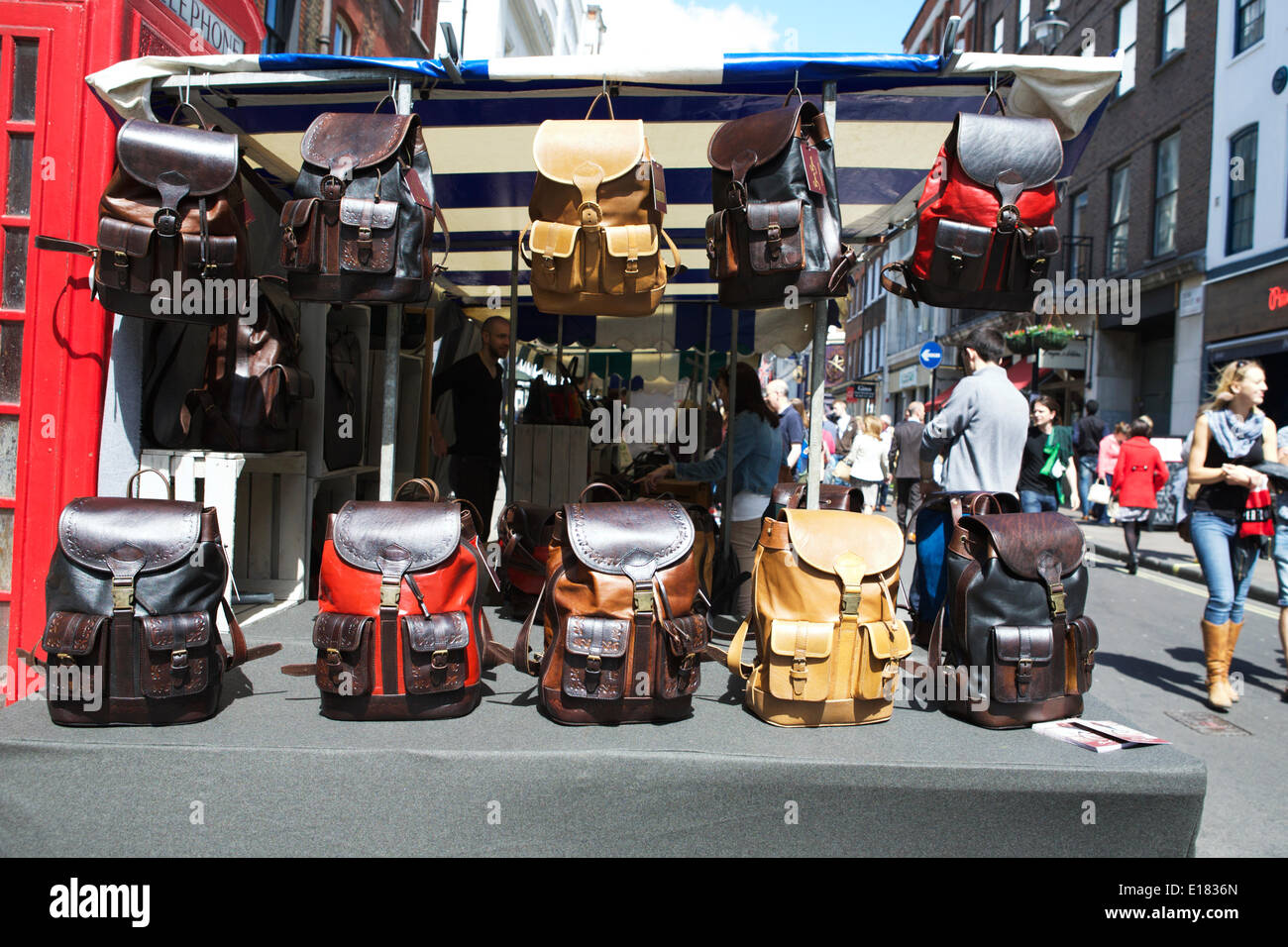 London street market: Soho il Mercato delle Pulci, Dean Street, Londra, Regno Unito. Un vivace mercato con turisti e popolazione locale e le bancarelle del mercato. Designer ruck sacchi per la vendita. Vetrina della città dei mercati. Foto Stock