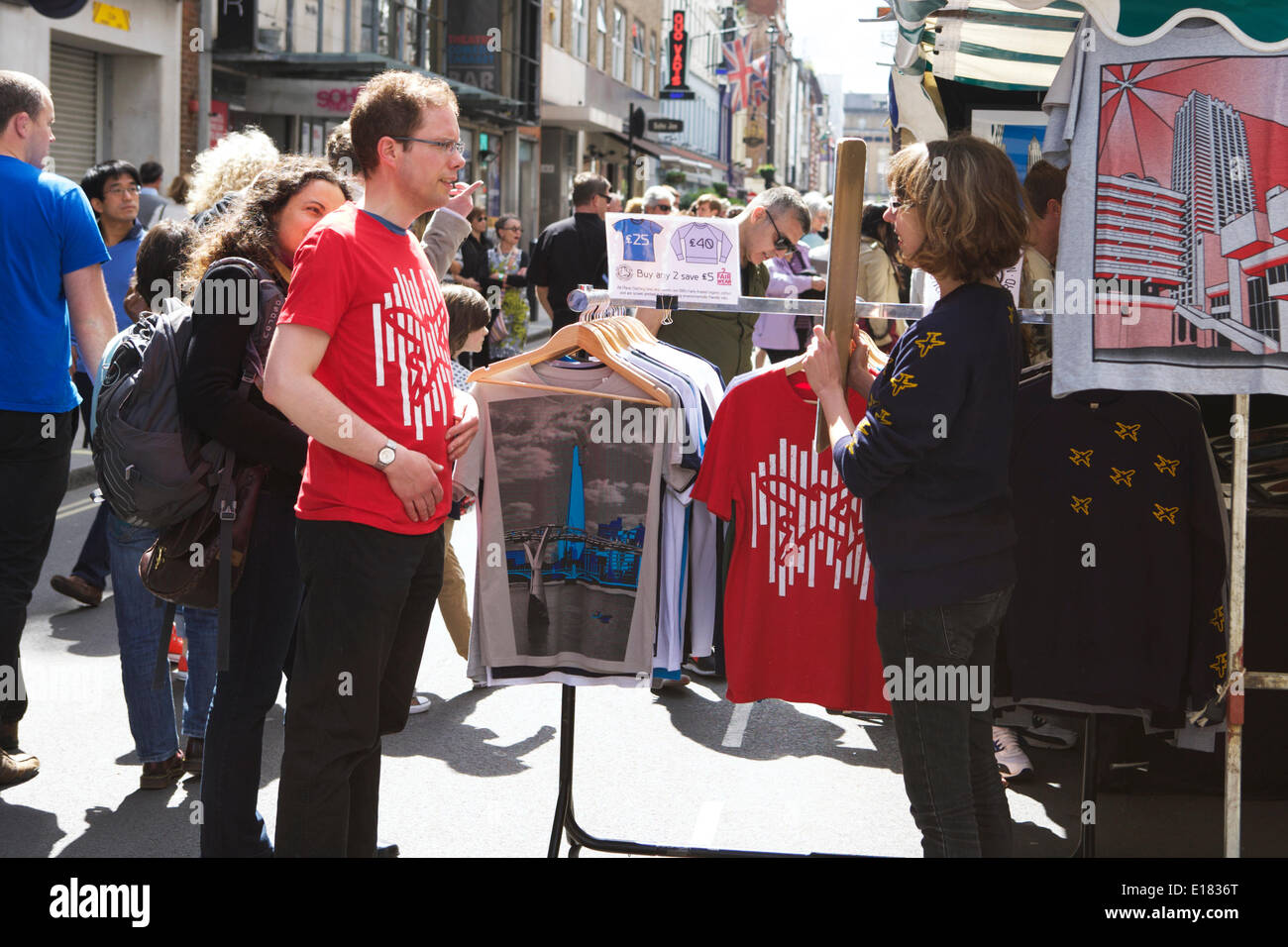 London street market: Soho il Mercato delle Pulci, Dean Street, Londra, Regno Unito. Un vivace mercato con turisti e popolazione locale e le bancarelle del mercato. Designer di T-shirt in vendita. Vetrina della città dei mercati. Foto Stock