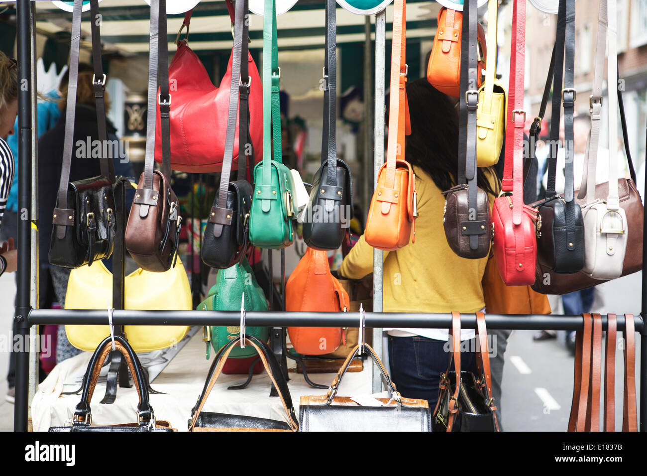 London street market: Soho il Mercato delle Pulci, Dean Street, Londra, Regno Unito. Un vivace mercato con turisti e gente locale. Colorata borse a mano visualizzata su un mercato in stallo. Vetrina della città dei mercati. Foto Stock