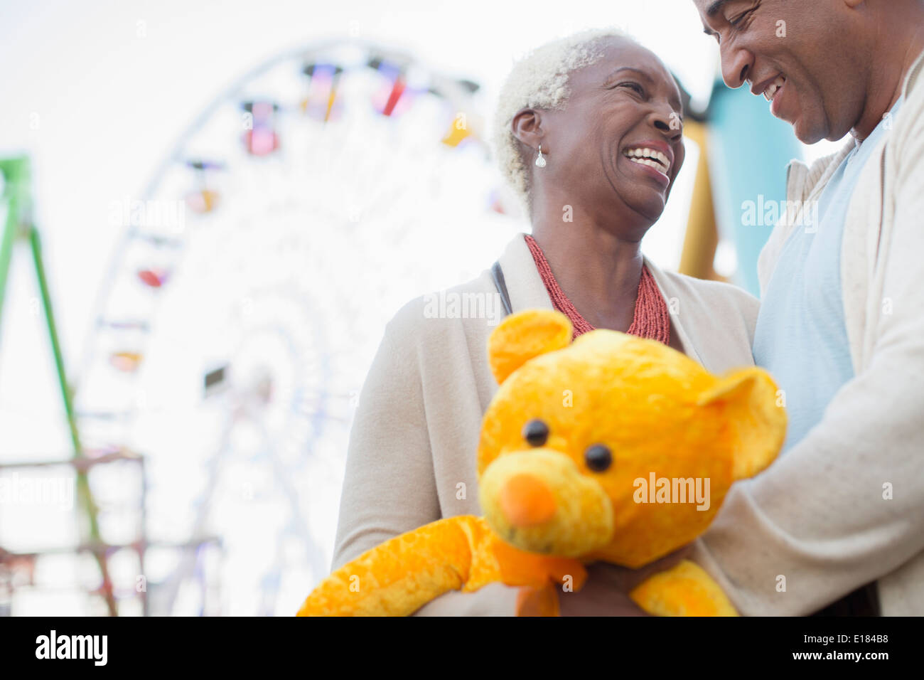 Coppia senior con Teddy bear abbracciando presso il parco di divertimenti Foto Stock