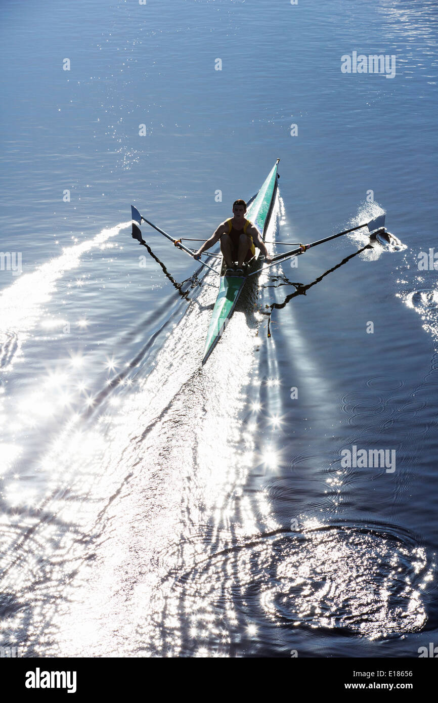 Uomo scull canottaggio sul lago Foto Stock