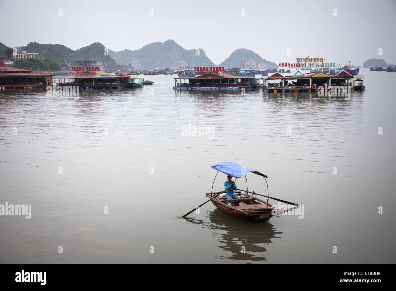 Un barcaiolo remare verso riva in cerca di clienti per i ristoranti che si trovano nel mezzo della baia. Foto Stock