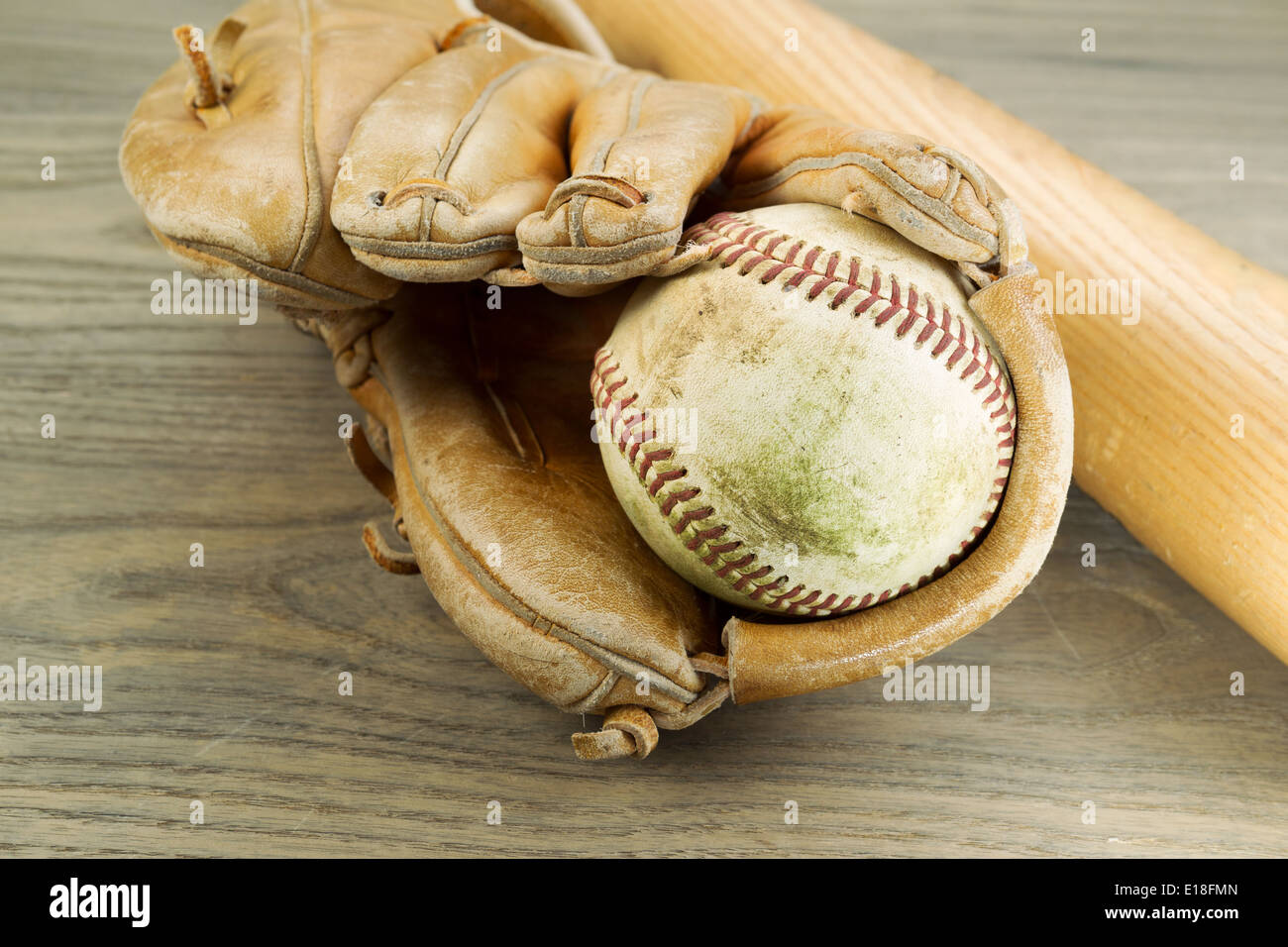 Closeup foto orizzontale di un vecchio e sporco all'interno di baseball di usato pesantemente guanto e mazza di legno in background su legno rustico Foto Stock