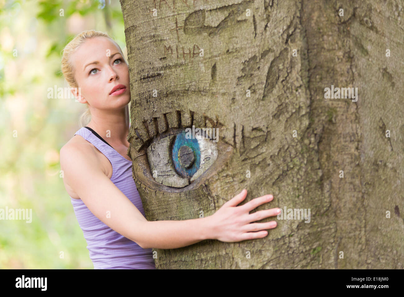 Giovane donna che abbraccia un albero. Foto Stock
