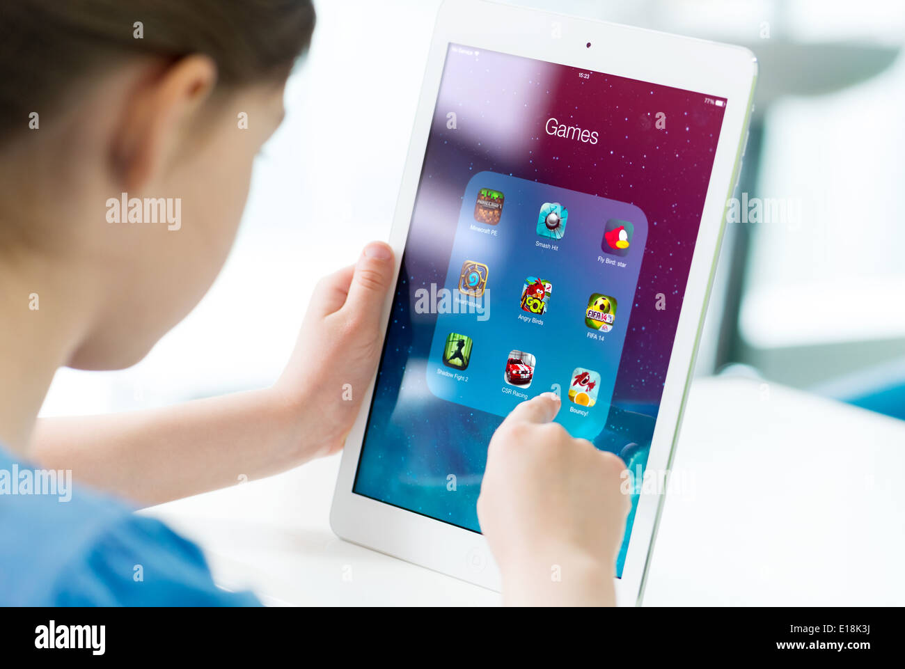 Bambina cerca su un marchio nuovo Apple iPad aria con varie applicazioni di gioco su una schermata Foto Stock