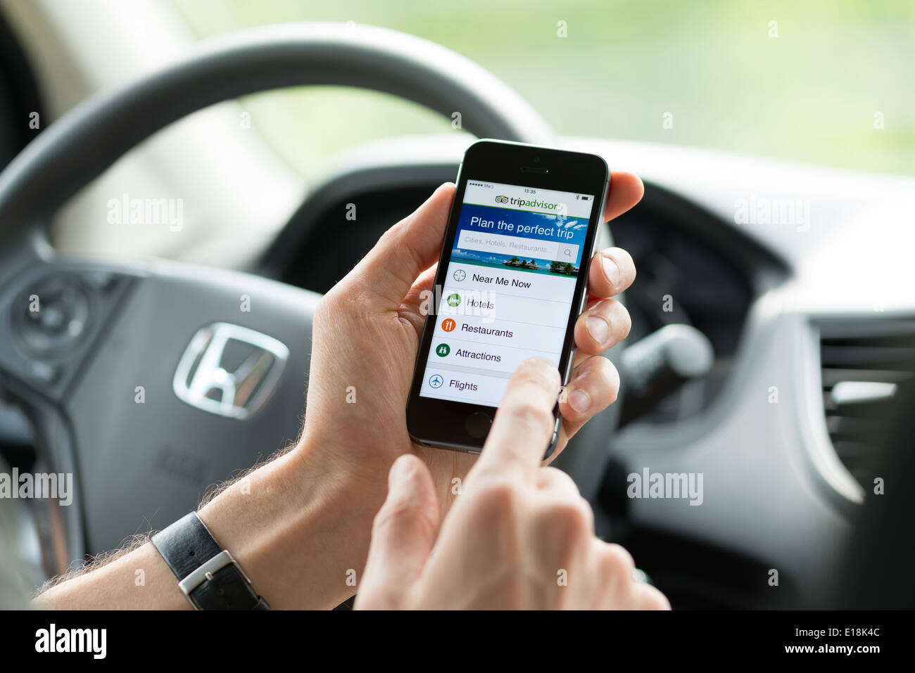 Uomo in un auto di pianificazione di un viaggio usando Tripadvisor app su Apple iPhone 5S Foto Stock