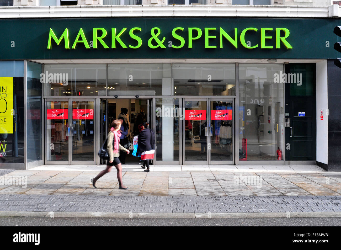 Una donna cammina davanti di Marks & Spencer store, Hammersmith, London, Regno Unito Foto Stock