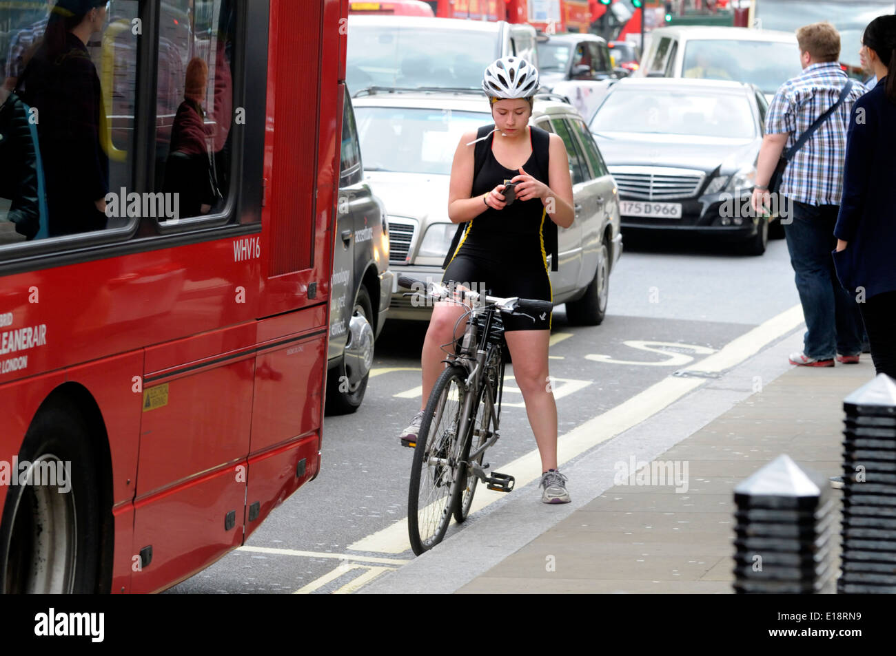 Londra, Inghilterra, Regno Unito. Ciclista femmina arrestato in Whitehall utilizzando il suo telefono cellulare Foto Stock