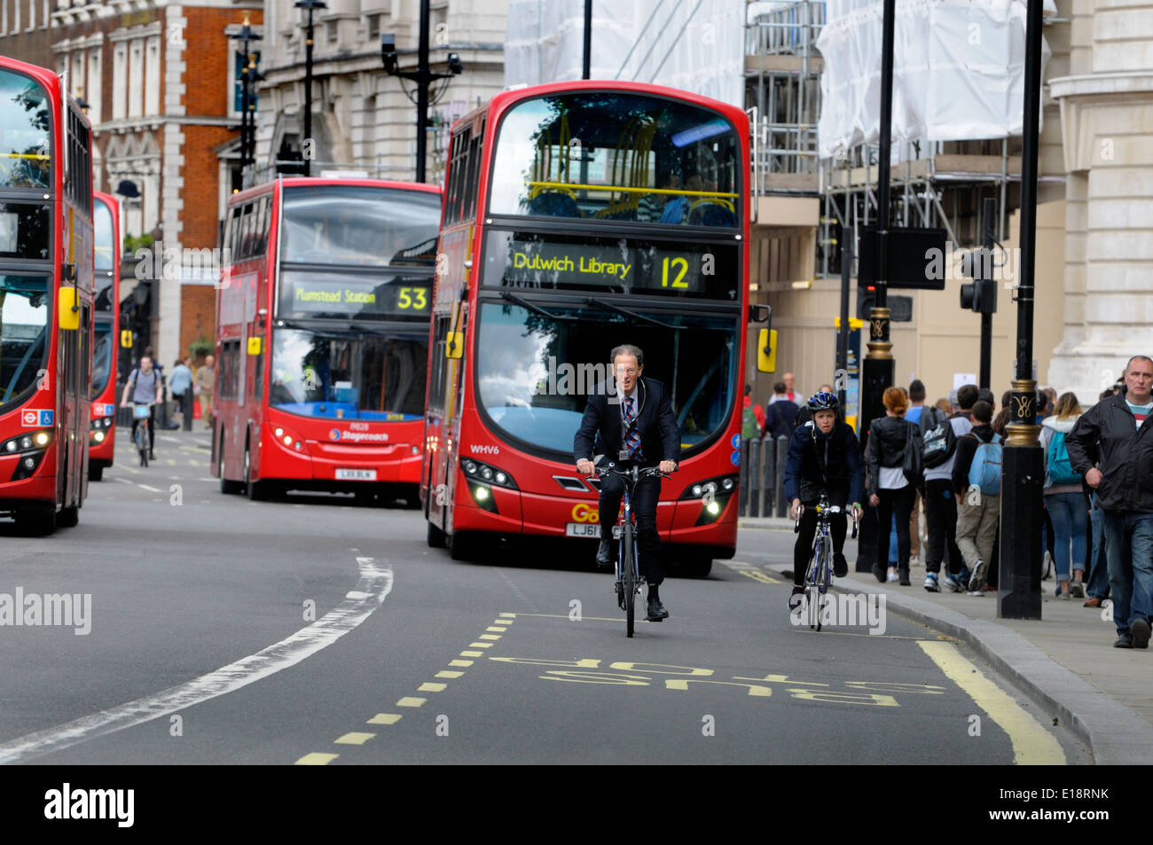 Londra, Inghilterra, Regno Unito. Ciclista in Whitehall, con il traffico e gli autobus Foto Stock