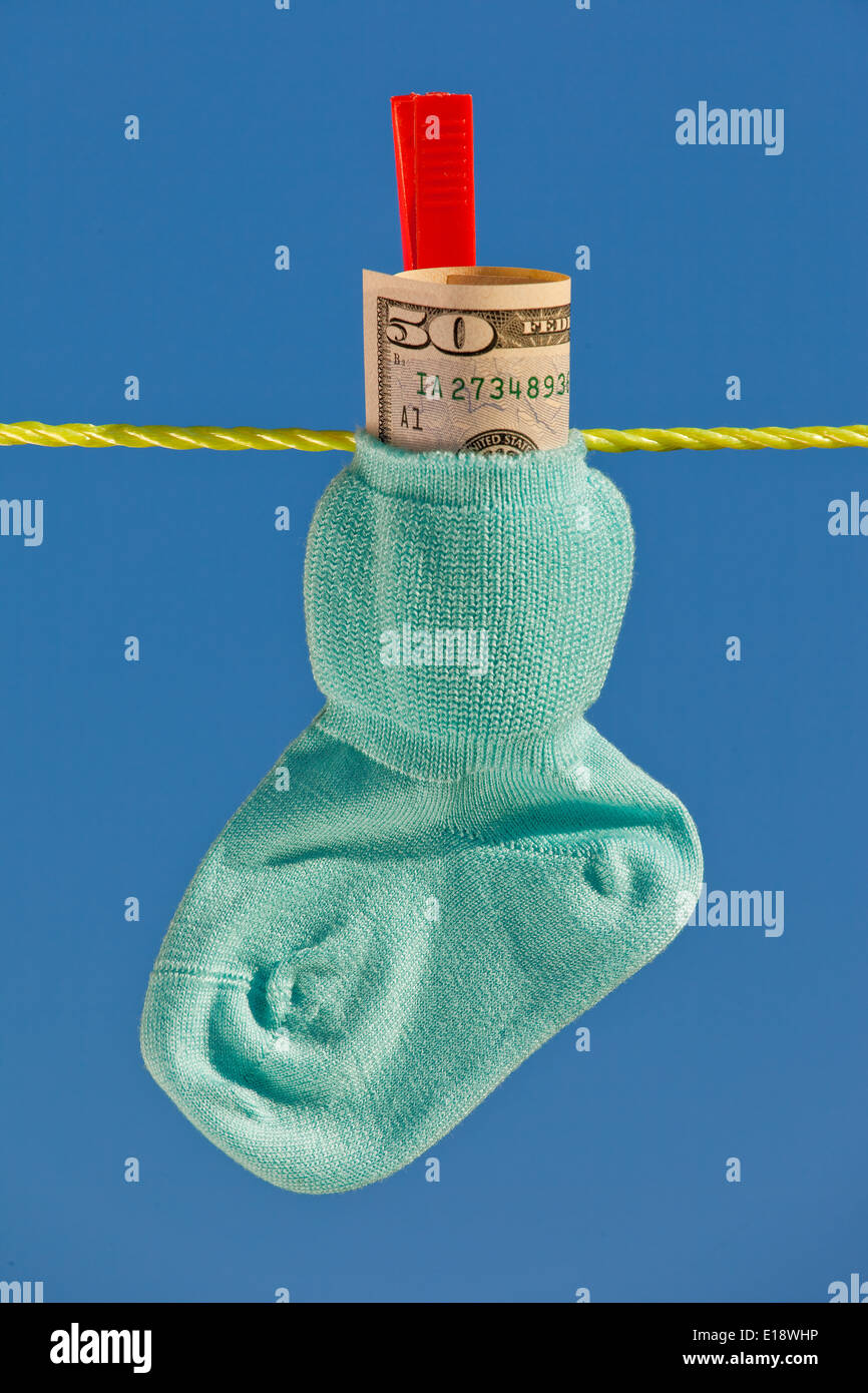 Baby Socken auf W‰scheleine mit Dollar Geldscheinen. Il Blauer Himmel. Foto Stock