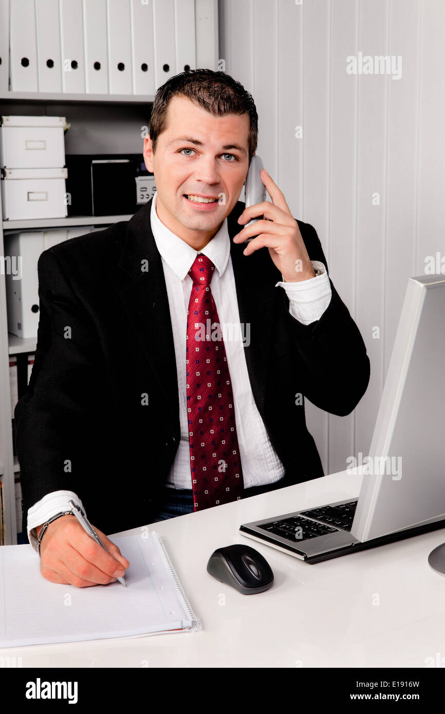 Junger Gesch‰ftsmann im B'ro mit Telefon Foto Stock