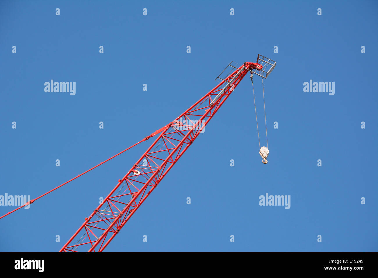 Rosso del braccio della gru che arrivano fino ad alta contro un cielo blu chiaro Foto Stock