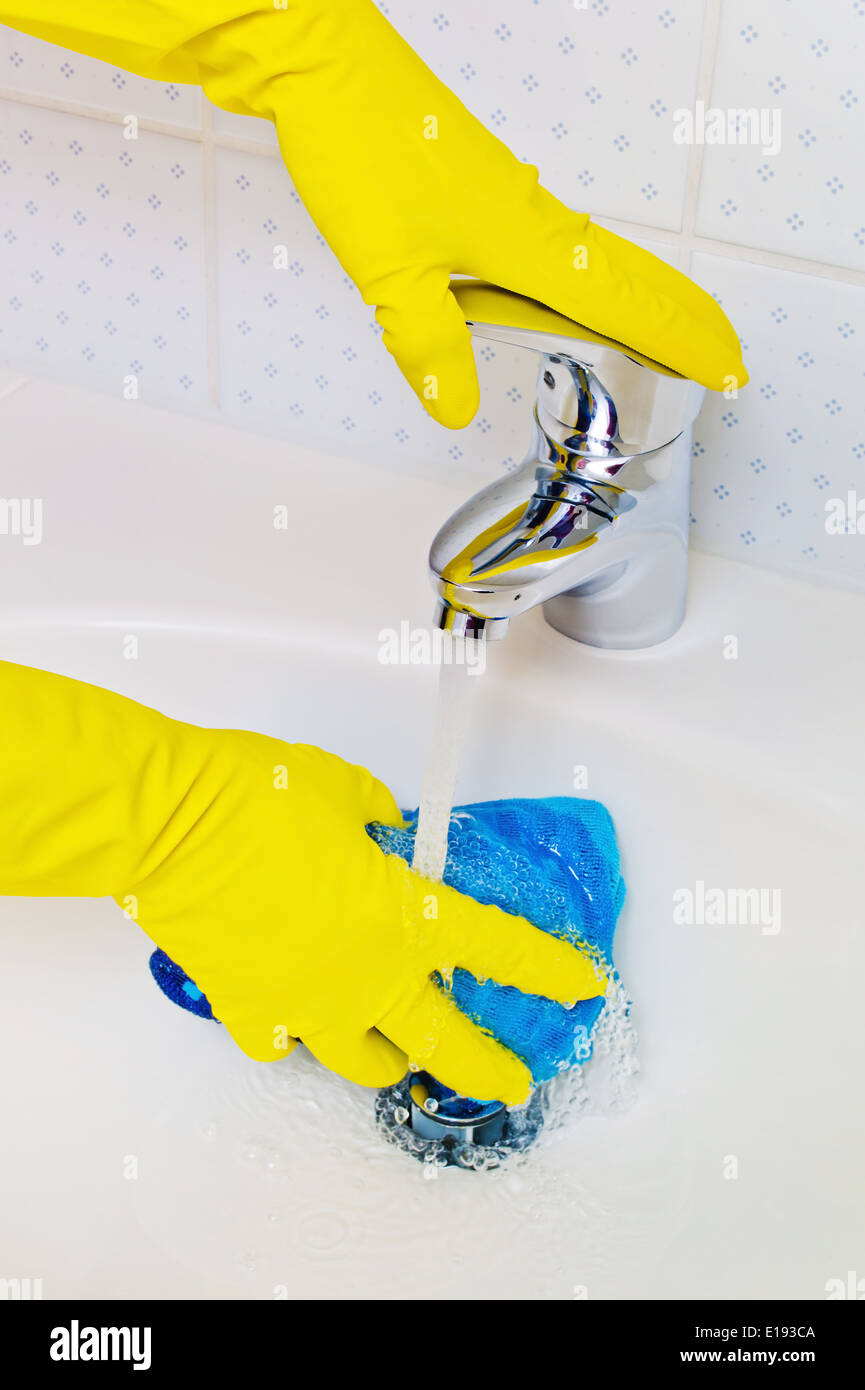 Das Waschbecken eines Badezimmers wird mit Handschuhen lattice gereinigt. Foto Stock
