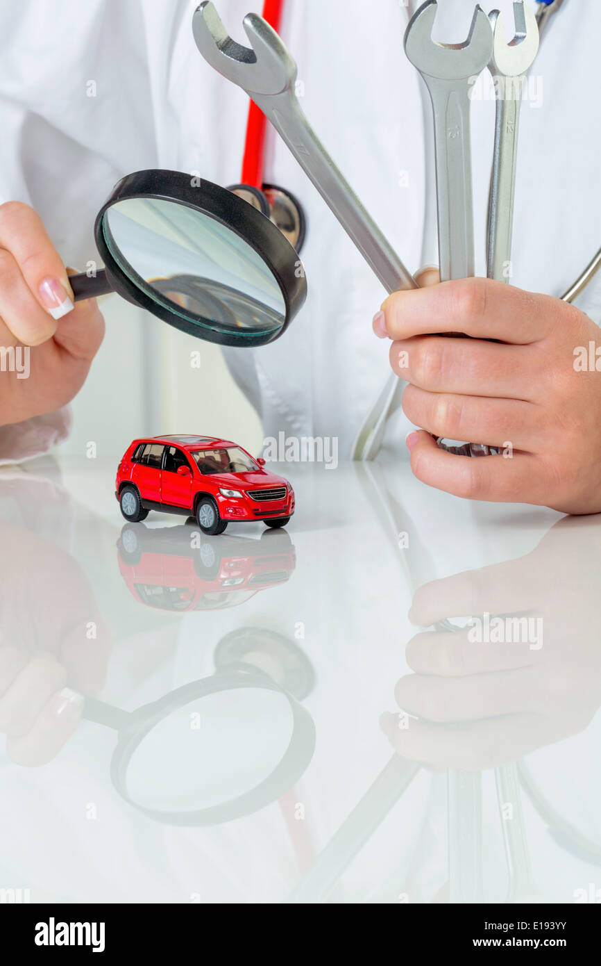 Ein Modell eines Autos wird von einem Arzt untersucht. Symbolfoto f'r Werkstatt, Service und Autokauf. Foto Stock