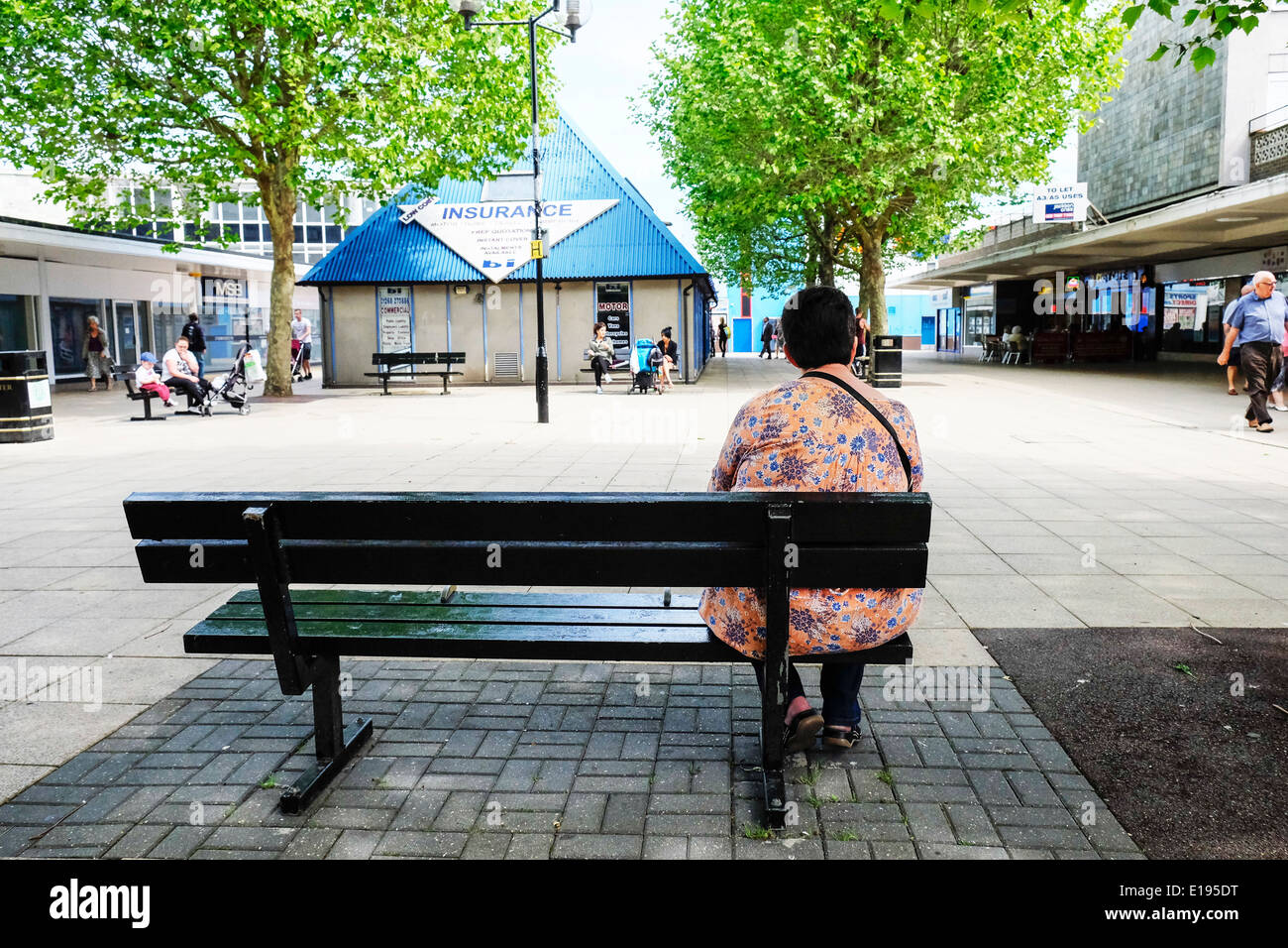 Una donna seduta su una panchina sul suo proprio. Foto Stock