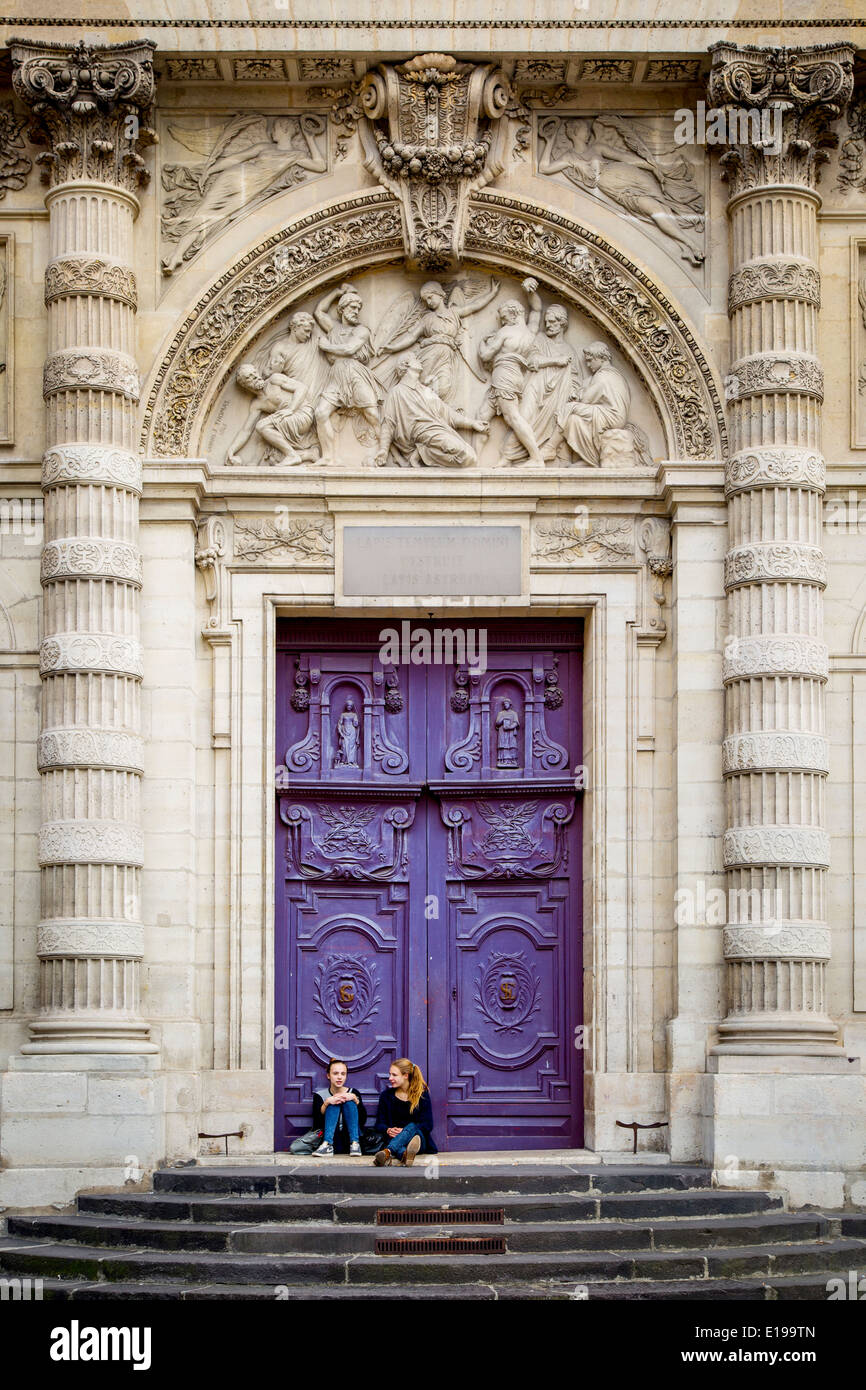 Due ragazze in enormi porte di legno a Saint Etienne du Mont Chiesa, Quartiere Latino, Parigi Francia Foto Stock