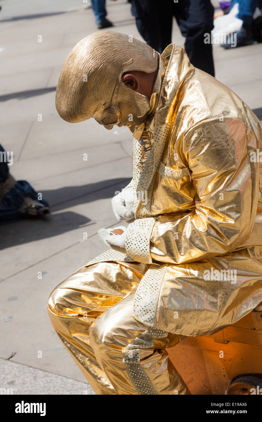 Statua vivente di una Oro elvis in Piccadilly Circus a Londra il suo conteggio incassi. Foto Stock